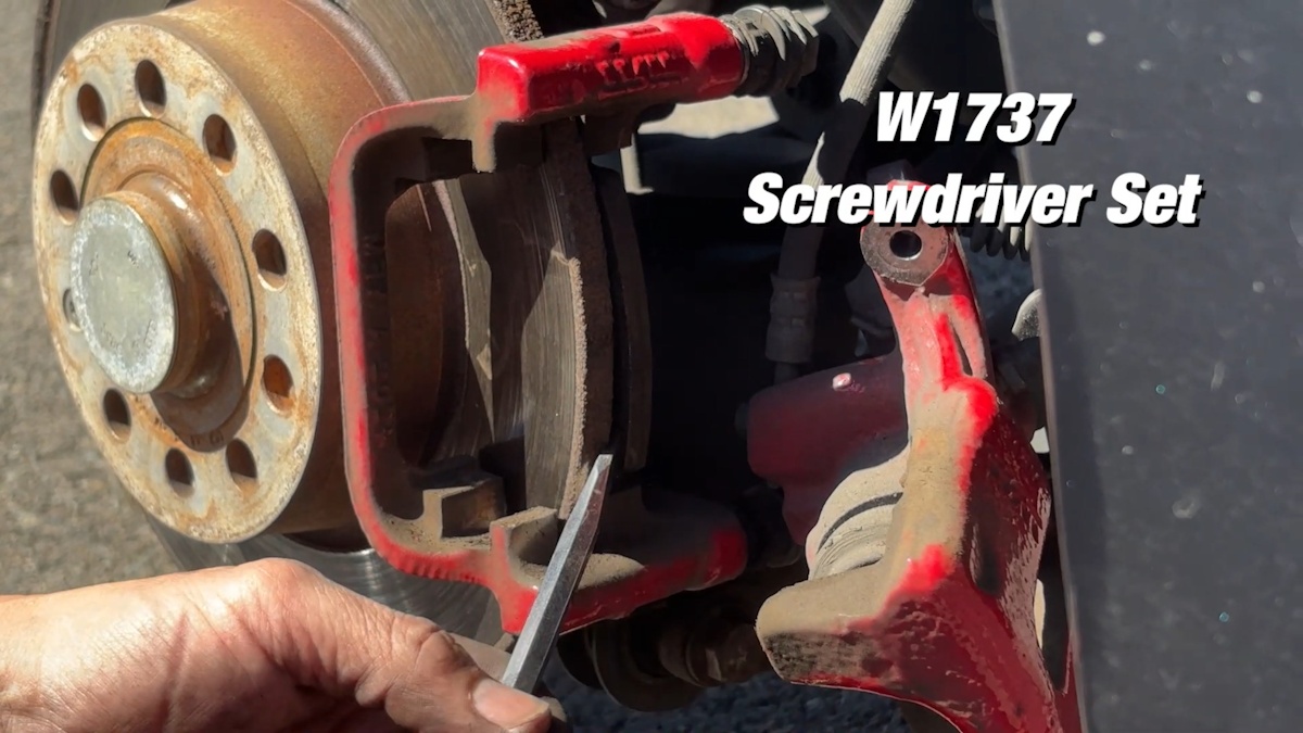 Using screwdriver to lift old brake pads from rotor