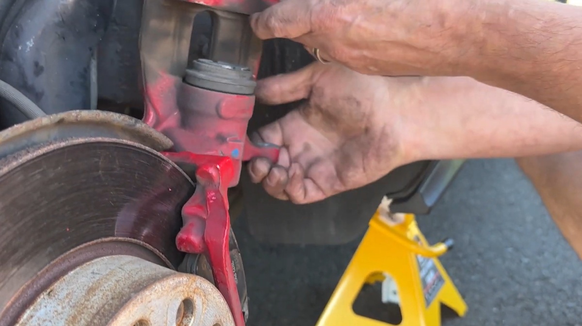 Carefully remove the brake caliper without straining the brake hose Lifting the brake caliper away from the rotor